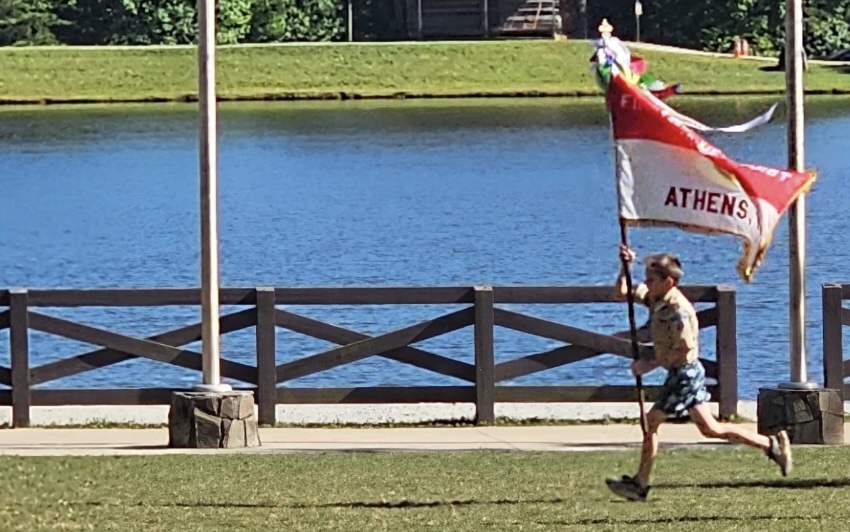 Scout carrying the Athens Troop 1 flag near the water